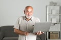 Grandfather, portrait of senior man with a laptop. Senior man with a gray beard at home. Mature man using computer.