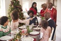 Grandfather pouring champagne at the dinner table during a multi generation, mixed race family Christmas celebration