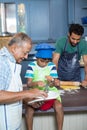 Grandfather showing tablet computer to boy while preparing food