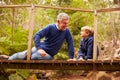 Grandfather sitting with grandson on a bridge in a forest
