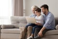 Grandfather son and grandson using laptop sitting on couch indoors Royalty Free Stock Photo