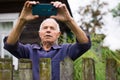 Grandfather takes selfie in front of his country house in village