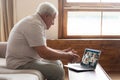 Grandfather talking with friends using pc webcam and videoconference app