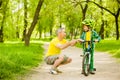 Grandfather talking with his grandson riding a bicycle and showing thumbs up Royalty Free Stock Photo