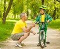 Grandfather talking with his grandson riding a bicycle and showing thumbs up Royalty Free Stock Photo