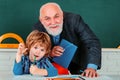 Grandfather teacher with grandson pupil at back of classroom at the elementary school. Science education concept. Royalty Free Stock Photo
