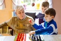 Grandfather and two kids boys playing strategy table game together. Senior man having fun with his grandchildren Royalty Free Stock Photo