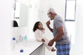 Grandfather Wearing Pajamas In Bathroom Shaving Whilst Granddaughter Watches