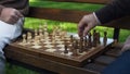 Grandfathers playing chess on bench, moving figures on board, game beginning