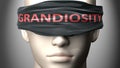 Grandiosity can make things harder to see or makes us blind to the reality - pictured as word Grandiosity on a blindfold to Royalty Free Stock Photo