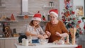 Grandma breaking egg helping grandchild preparing festive cookie dough in culinary kitchen