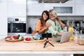 Grandma and daughter record a cooking vlog or podcast while chopping vegetables for a healthy vegetarian meal in the kitchen and Royalty Free Stock Photo