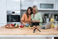 Grandma and daughter record a cooking vlog or podcast while chopping vegetables for a healthy vegetarian meal in the kitchen and Royalty Free Stock Photo