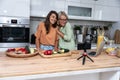 Grandma and daughter record a cooking vlog or podcast while chopping vegetables for a healthy vegetarian meal in the kitchen and Royalty Free Stock Photo