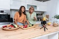 Grandma and daughter record a cooking vlog or podcast while chopping vegetables for a healthy vegetarian meal in the kitchen and Royalty Free Stock Photo