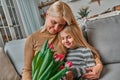 Grandma, this gift is for you! Little beautiful blonde granddaughter gives her grandmother a bouquet of pink tulips. The concept Royalty Free Stock Photo