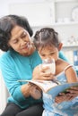 Grandma giving milk to her granddaugter Royalty Free Stock Photo