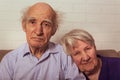 Grandma and grandpa cuddling together on couch.