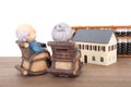 Grandma and grandpa sitting in rocking chair looking at house model and abacus tool in the distance Royalty Free Stock Photo