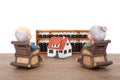 Grandma and grandpa sitting in rocking chair looking at house model and abacus tool in the distance Royalty Free Stock Photo