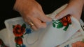 Grandma hand embroider a cross-stitch.