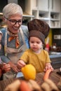 Grandma with her grandson with a funny cook hat in the kitchen