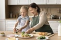 Grandma in kitchen apron teaching little granddaughter kid to cook Royalty Free Stock Photo