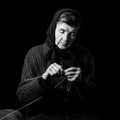 Grandma knitting. Black-and-white low key photograph on black background.