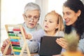 Grandma, mother and girl on tablet for education in home for lesson, homework and learning math online. Grandparent