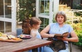 Grandma reads fairy tales to lovely girl while spending time together on sunny terrace near house Royalty Free Stock Photo