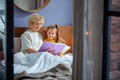 grandma reads tales to little daughter lying on bed in children& x27;s room Royalty Free Stock Photo