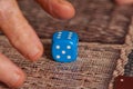 Grandma rolls a blue dice.Social game. Throwing a blue cube