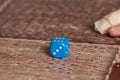Grandma rolls a blue dice.Social game. Throwing a blue cube
