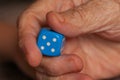 Grandma rolls a blue dice.Social game. Throwing a blue cube