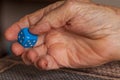 Grandma rolls a blue dice.Social game. Throwing a blue cube