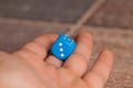 Grandma rolls a blue dice.Social game. Throwing a blue cube