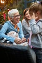 Grandma showing birthday present to her granddaughter. Mother of a little girl in the background. Love, affection, joy, three Royalty Free Stock Photo