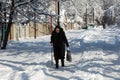 Grandma with a stick is walking along a snowy street. Problems of old people. The war in the Donbas