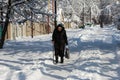 Grandma with a stick is walking along a snowy street. Problems of old people. The war in the Donbas