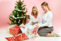 Grandmother with adult daughter and grandchild. under the christmas tree, opening presents