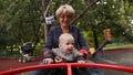 Grandmother and baby happy to revolve the carousel in the park in the summer.