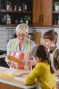 Grandmother baking cookies with her grandchildren at home