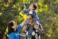 Grandmother with boy holding toy airplane sitting on grandfather`s shoulder at park Royalty Free Stock Photo
