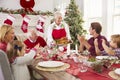 Grandmother Bringing Out Turkey At Family Christmas Meal