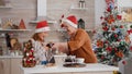 Grandmother bringing wrapper present gift with ribbon on it to granddaughter enjoying christmastime Royalty Free Stock Photo