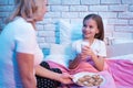 Grandmother brings granddaughter cookies and milk at night at home. Royalty Free Stock Photo
