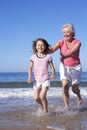 Grandmother Chasing Granddaughter Along Beach Royalty Free Stock Photo