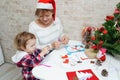 Grandmother and child girl in Santa hat making christmas greeting card with snowman Royalty Free Stock Photo