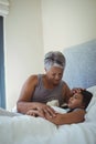 Grandmother comforting sick granddaughter in bed room Royalty Free Stock Photo