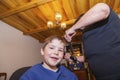 Boy is having a haircut at home by grandmother